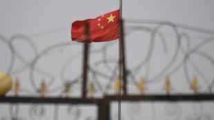 This photo taken on June 4, 2019 shows the Chinese flag behind razor wire at a housing compound in Yangisar, south of Kashgar, in China's western Xinjiang region.