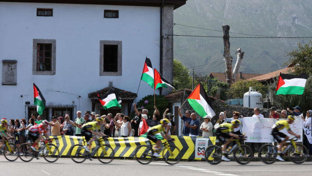 Os ciclistas passam por manifestantes com bandeiras da Palestina durante a etapa 13 da "Vuelta a Espana", em Cabezon de la Sal a L'angliru, Cantábria, Espanha em 5 de setembro de 2025.