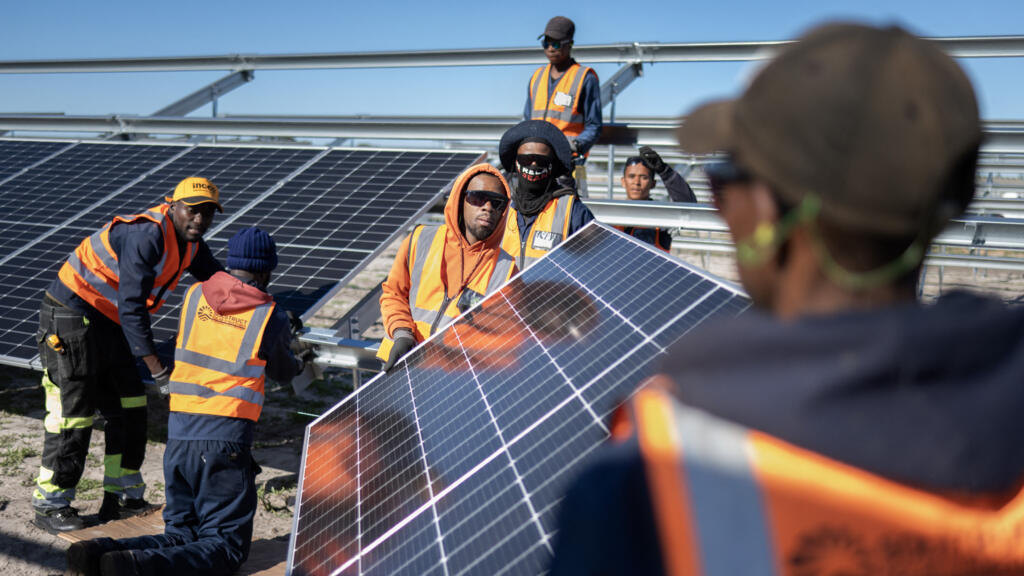 Des ouvriers installent des panneaux solaires sur des cadres lors de la construction de la première centrale solaire municipale d'Afrique du Sud, le 5 juin 2025, à Atlantis, à environ 40 km du Cap.