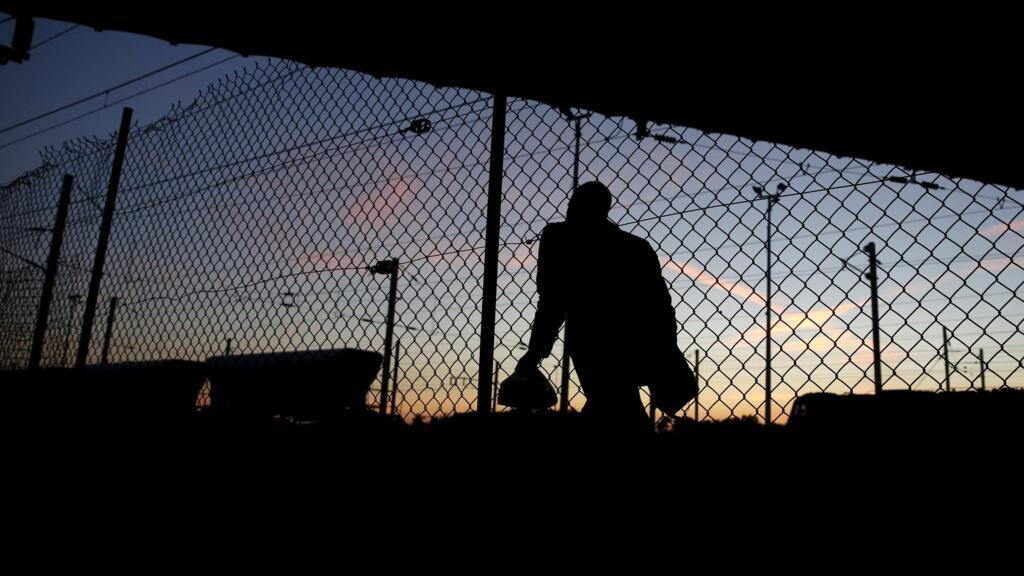Un migrant africain tente de traverser les grilles interdisant le passage vers le Tunnel sous la Manche, près de Calais, le 8 août 2015.