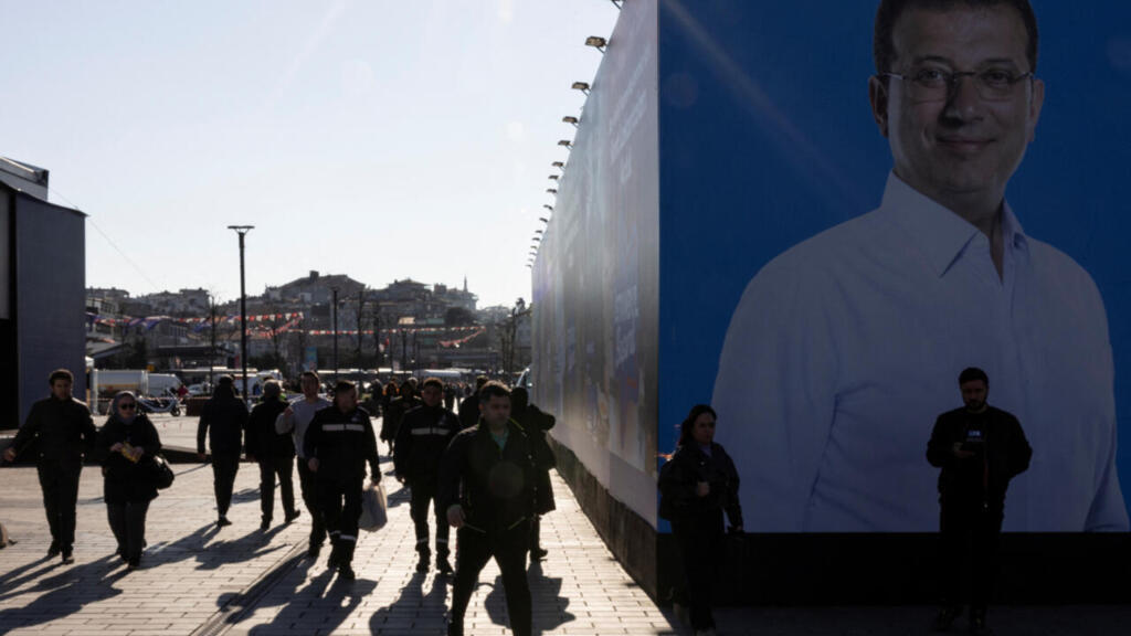 People walk past a portrait of Istanbul's mayor Ekrem Imamoglu hung on a campaign tent in Istanbul, Turkey, February 20, 2024.