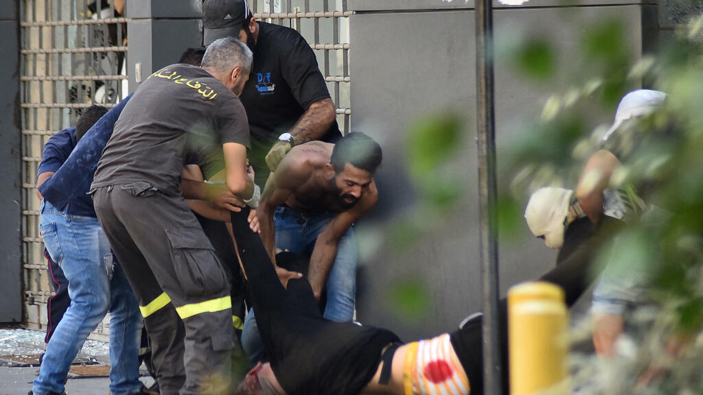 Des membres de la défense civile libanaise et des passants portent secours à un homme après des tirs visant des manifestants à Beyrouth, le 14 octobre 2021.