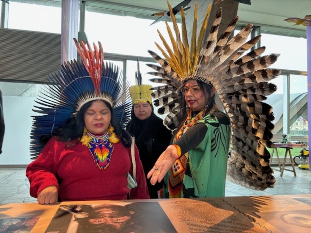 A curadora Daiara Tukano, à direita, explica o conteúdo da mostra na Unesco à ministra Sonia Guajarara, em Paris, 12/03/24.