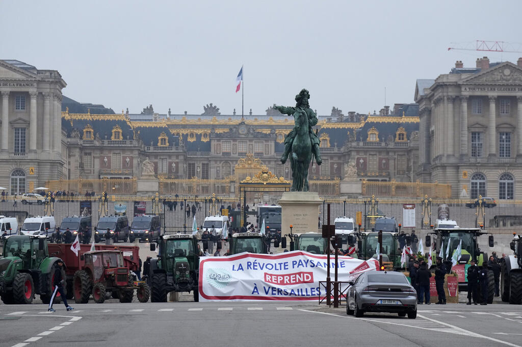 Farmers behind a banner reading "The farmers revolt resumes in Versailles" demonstrate outside the Chateau de Versailles to protest against the planned EU-Mercosur trade deal, Friday, Sept. 26, 2025 i