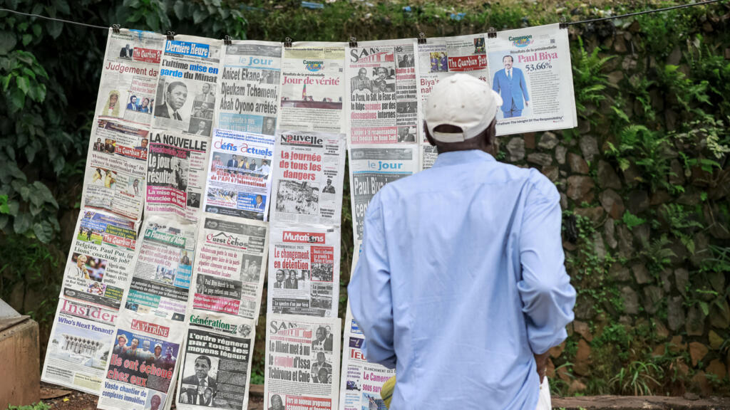 Un piéton consulte les gros titres des journaux dans un kiosque à Yaoundé, le 28 octobre 2025, au lendemain de l'annonce des résultats de l'élection présidentielle au Cameroun. Le président camerounais Paul Biya, âgé de 92 ans, a été réélu pour un huitième mandat avec 53,7 % des voix, selon les résultats officiels annoncés par le Conseil constitutionnel le 27 octobre 2025.