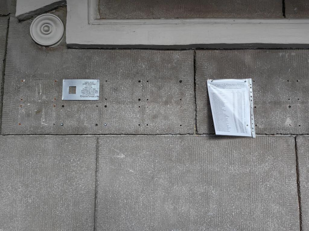 Ici, le 65 boulevard Lesnaya à Saint-Pétersbourg. Des plaques du mouvement « Ancienne adresse » ont été arrachées. À la place : une feuille sous plastique qui égrène les noms.