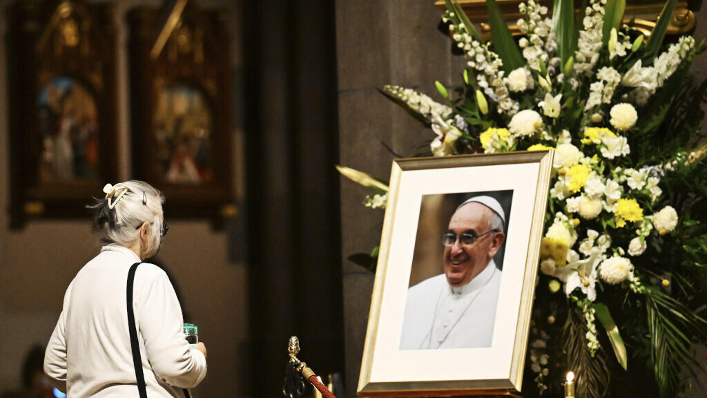 Une femme regarde une photo du pape François à l'intérieur de la cathédrale Saint-Patrick avant une messe à Melbourne, en Australie, le mardi 22 avril 2025.