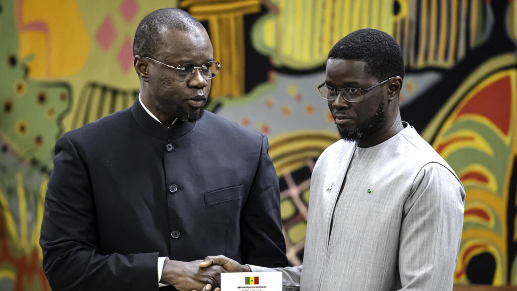 Le Premier ministre sénégalais Ousmane Sonko (à gauche) remet au président sénégalais Bassirou Diomaye Faye (à droite) le rapport officiel sur le massacre de Thiaroye lors d'une cérémonie au palais présidentiel à Dakar, le 16 octobre 2025.