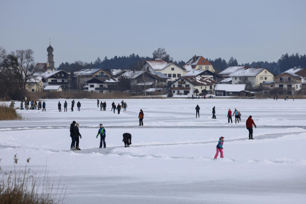 People ice skate over the frozen Klostersee lake close to Seeon Abbey in southern Germany
