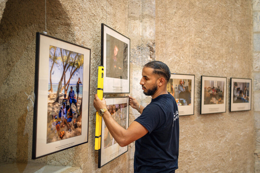 Un employé installe des photographies de l'exposition « Grandir dans la cour d'écrans » de Jérôme Gence lors de la 36e édition du festival de photographie de presse « Visa pour l'image » à Perpignan, dans le sud-ouest de la France, le 28 août 2024.