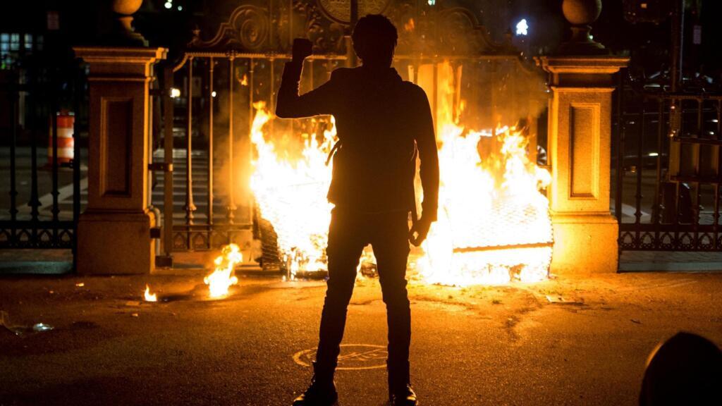 Un manifestant, poing levé, devant la porte en flammes du Boston Public Garden, le 31 mai 2020.