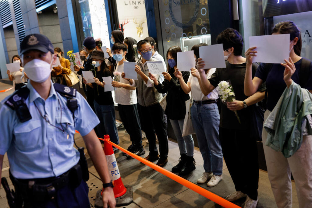 À Hong Kong, plusieurs personnes tiennent des feuilles blanches et des fleurs lors d'une manifestation contre les restrictions de Covid en Chine, le 28 novembre 2022.