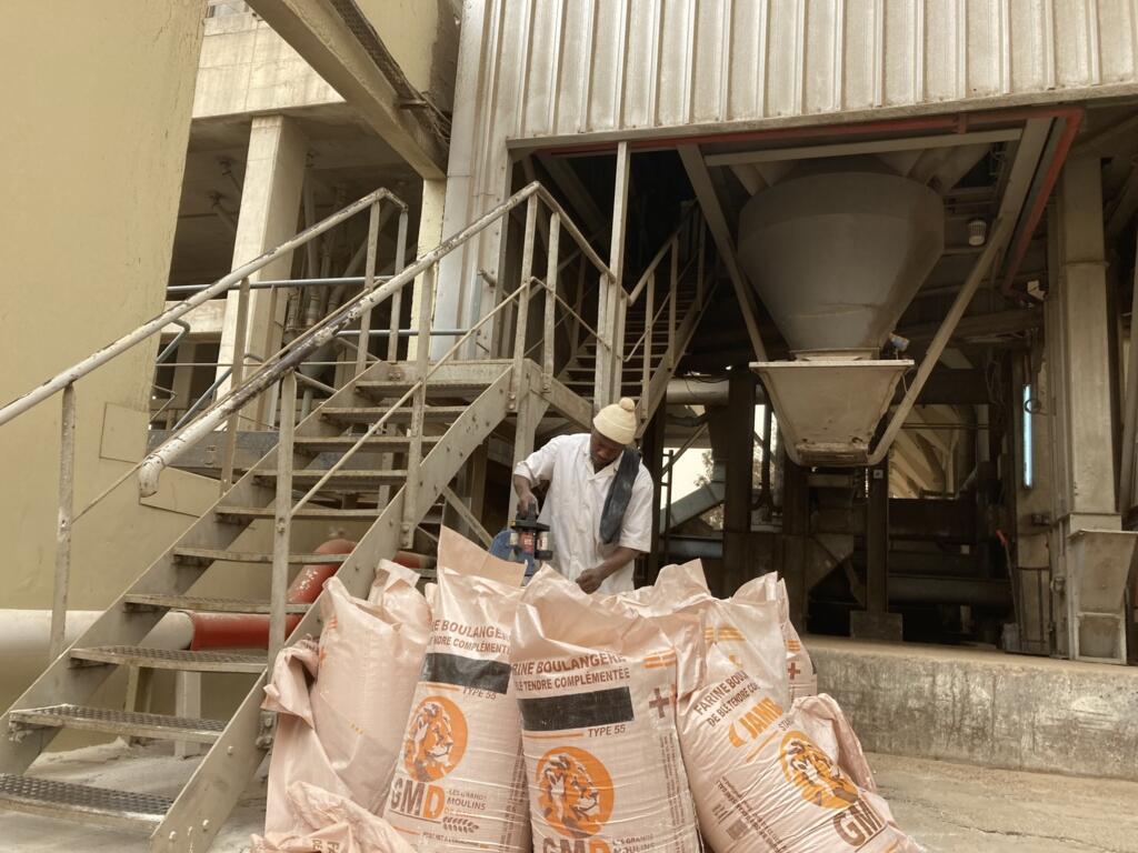 Un agent des Grands Moulins de Dakar ferme des sacs de farine vendus à 19 200 francs CFA le sac, un prix homologué par l'État alors qu'il devrait être vendu au prix de 26 000 francs CFA.