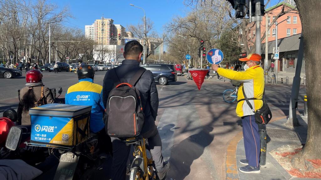 Un volontaire aide au passage piétons, Chine.