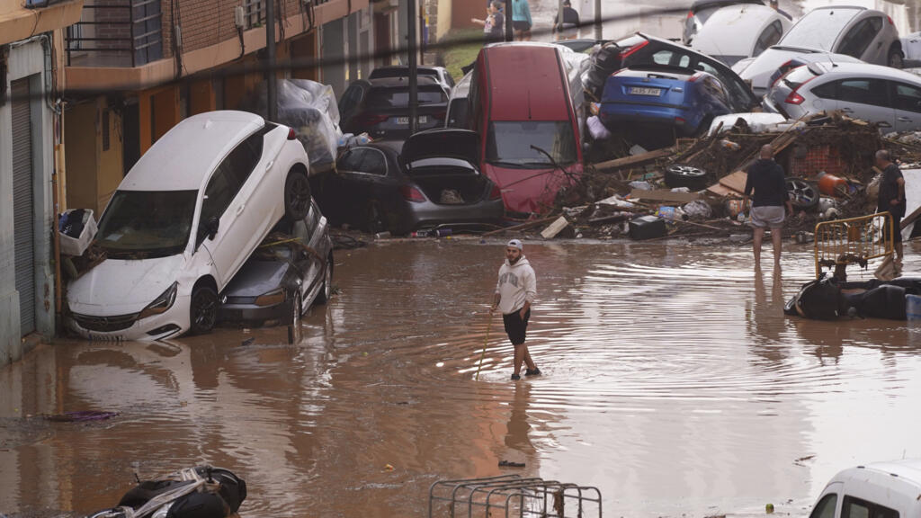 Des habitants regardent des voitures empilées après avoir été emportées par les inondations à Valence, en Espagne, mercredi 30 octobre 2024.