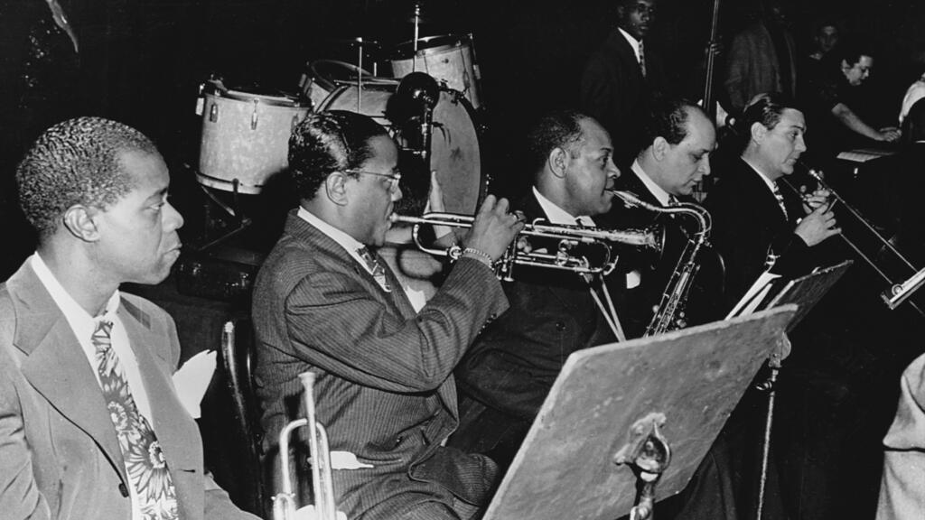 Les musiciens Louis Armstrong, Roy Eldridge, Coleman Hawkins, Barney Bigard, and Jack Teagarden, pendant un concert.