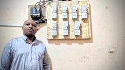 Mamadou pose devant l'installation électrique de son immeuble de la banlieue de Conakry (le 8 avril 2023).