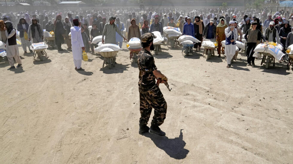 یک جنگجوی طالبان در برابر شمار زیادی از مردمی که درحال انتقال جیره غذایی توزیع شده از سوی یک گروه کمک‌های بشردوستانه چینی در ماه رمضان هستند. 30 آوریل 2022