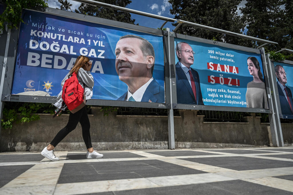 A woman walks past billboards, one showing Turkish President Recep Tayyip Erdogan (L) and another with the portrait of his opponent, Republican People's Party leader and presidential candidate Kemal Kilicdaroglu (R), on 28 April 2023.