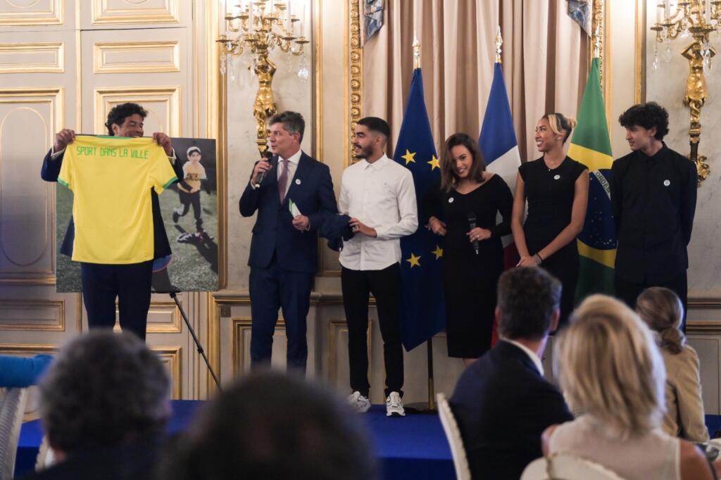 Ao lado de jovens beneficiados por intercâmbios, Raí recebe camisa da Seleção personalizada da Sport pour la Ville, associação francesa parceira da Gol de Letra. (25/09/2023)