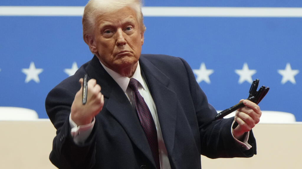 Le président Donald Trump lance à la foule des stylos utilisés pour signer des décrets lors d'un défilé intérieur d'investiture présidentielle à Washington, lundi 20 janvier 2025.