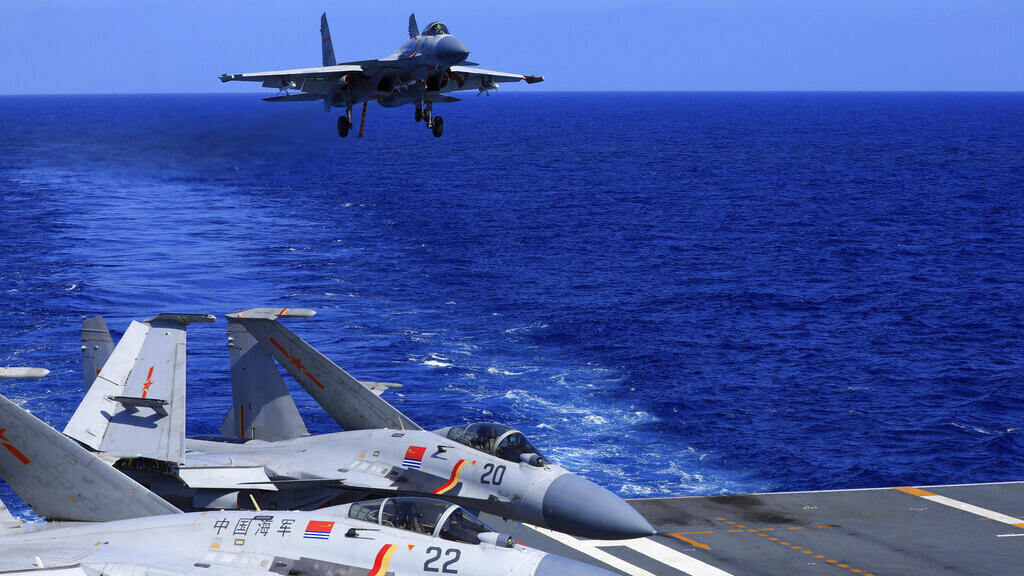 In this photo released Dec. 31, 2021, by Xinhua News Agency, an undated photo shows a carrier-based J-15 fighter jet preparing to land on the Chinese navy's Liaoning aircraft-carrier during open-sea c