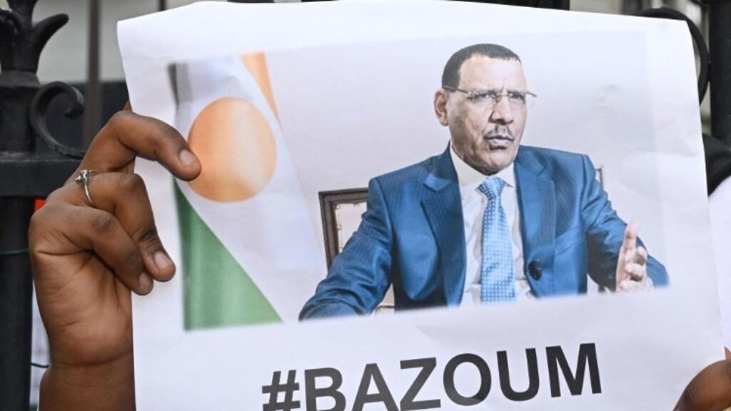 Une femme tient l'image du président déchu du Niger Mohamed Bazoum, 63 ans, détenu par les putschistes avec sa famille dans sa résidence officielle de Niamey depuis le 26 juillet, lors d'une manifestation devant l'ambassade du Niger, à Paris, le 5 août 2023.