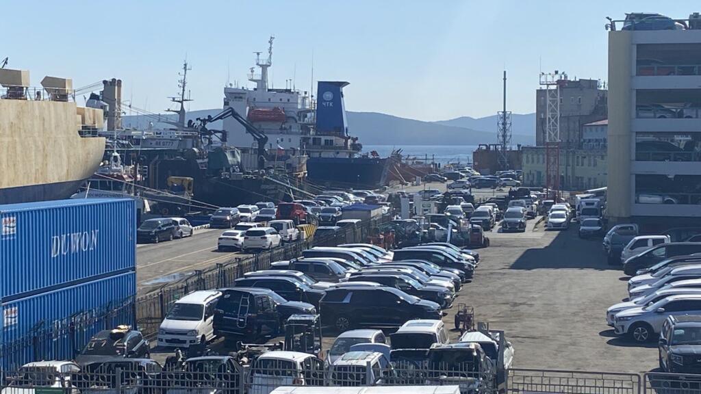 Au port de Vladivostok, des marchandises dont des voitures, sont en attente de livraison.