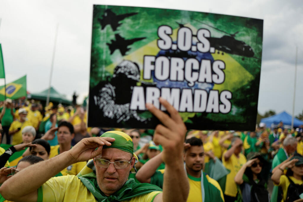 Um homem segura uma placa que diz "SOS Forças Armadas" durante um protesto realizado por apoiadores do presidente Jair Bolsonaro contra o eleito Luiz Inácio Lula da Silva, que ganhou um terceiro mandato após o segundo turno das eleições presidenciais, na sede do Exército em Brasília, Brasil, em 7 de novembro de 2022.