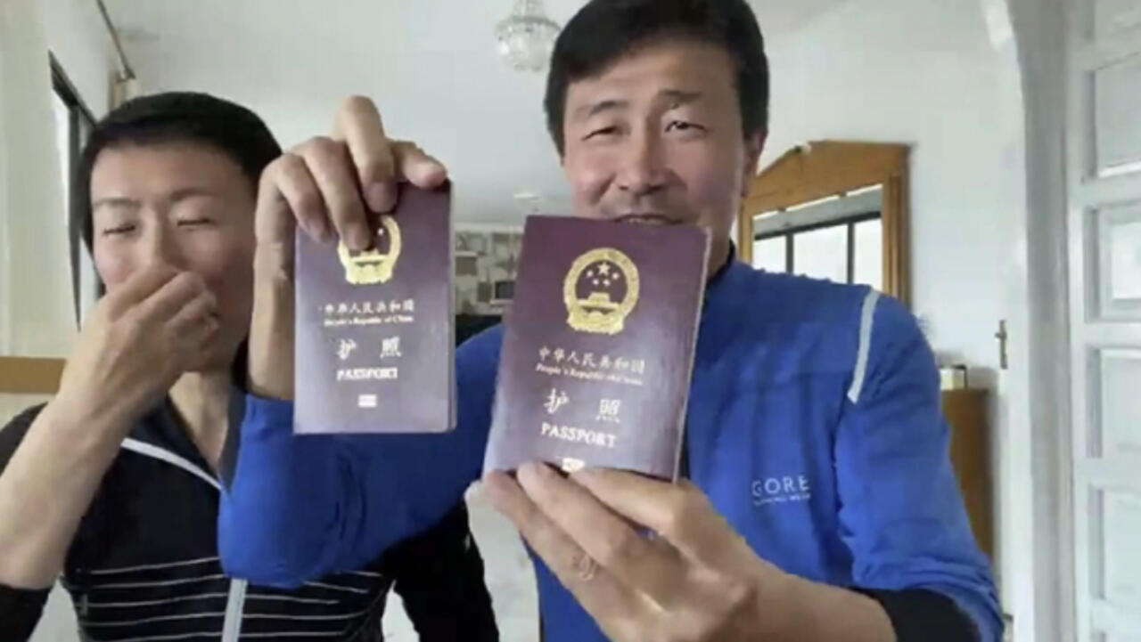 郝海东与妻子叶钊颖在西班牙举起中国护照。（苹果日报图片）