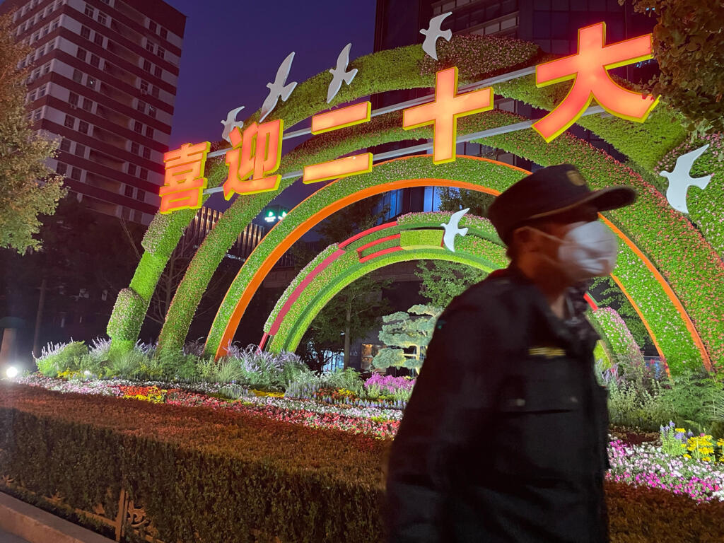 Un garde devant l’une des nombreuses décorations florales et parterres fleuris installés en ville à l’occasion du XXe congrès du PCC.