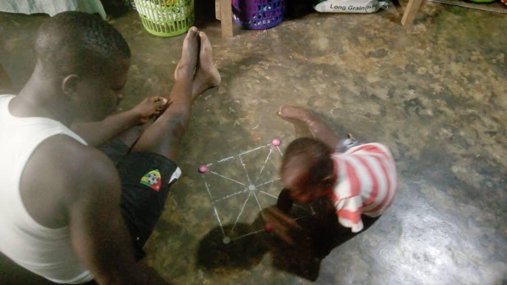 Mawuéna, 2 ans, initié au jeu du morpion par son père.