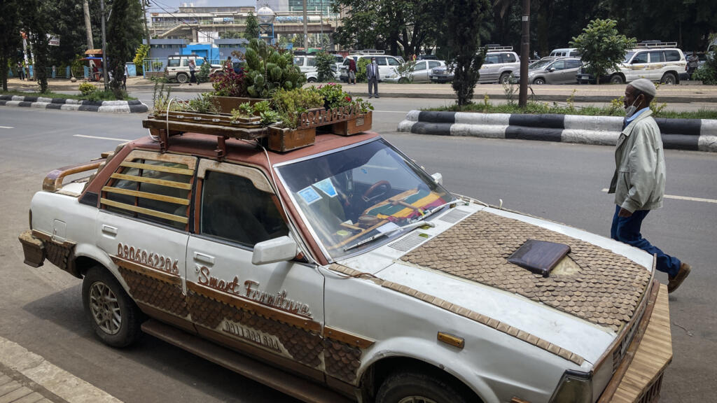 Un piéton passe devant une voiture recouverte de boiseries et avec un jardin de plantes en pot fixé sur le toit, faisant la publicité d'une entreprise de meubles et de design, dans le centre-ville d'Addis-Abeba, en Éthiopie, le lundi 28 juin 2021. (Image d'illustration)