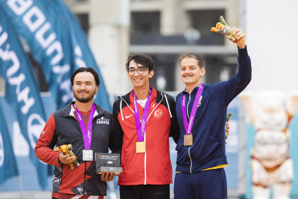 O brasileiro Marcus D’Almeida (esq.) celebra o bronze em Berlim, lado do canadense Eric Peters, que levou a prata, e o turco Mete Gazoz (dir.) que ficou em primeiro lugar.