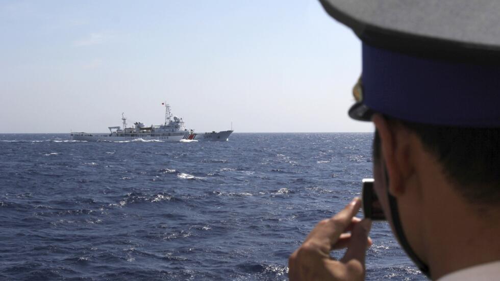 In this Thursday, May 15, 2014 photo, an officer on board Vietnam Coast Guard 4033 vessel films China Coast Guard 3411 vessel sailing in the waters claimed by both countries in the South China Sea.