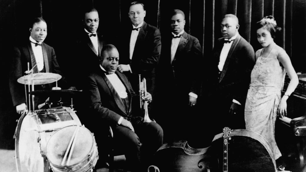 L’orchestre de King Oliver avec Baby Dodds (batterie), Honore Dutrey (trombone), King Oliver (assis, trompette lead), Bill Johnson (banjo), Louis Armstrong (trompette), Johnny Dodds (clarinette), et Lil Hardin (piano).
