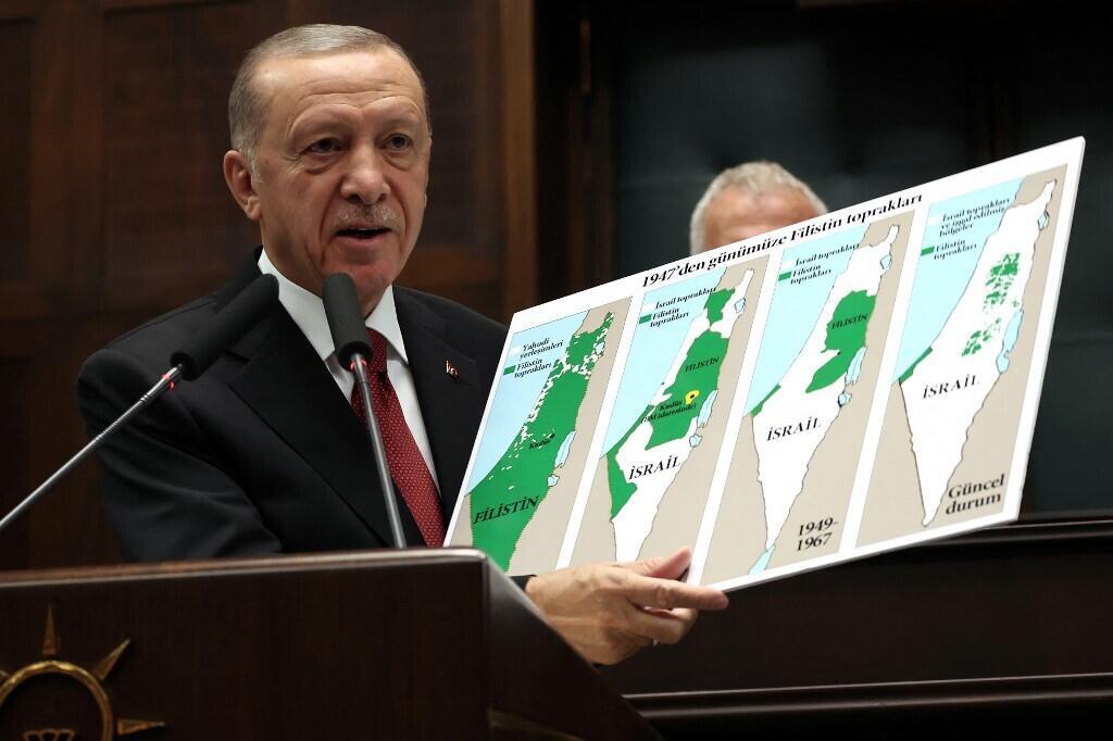 President Erdogan holds a sign showing the evolution of lands of Israel and Palestine on maps at his AK party's group meeting in the Turkish Grand National Assembly in Ankara on October 11, 2023.