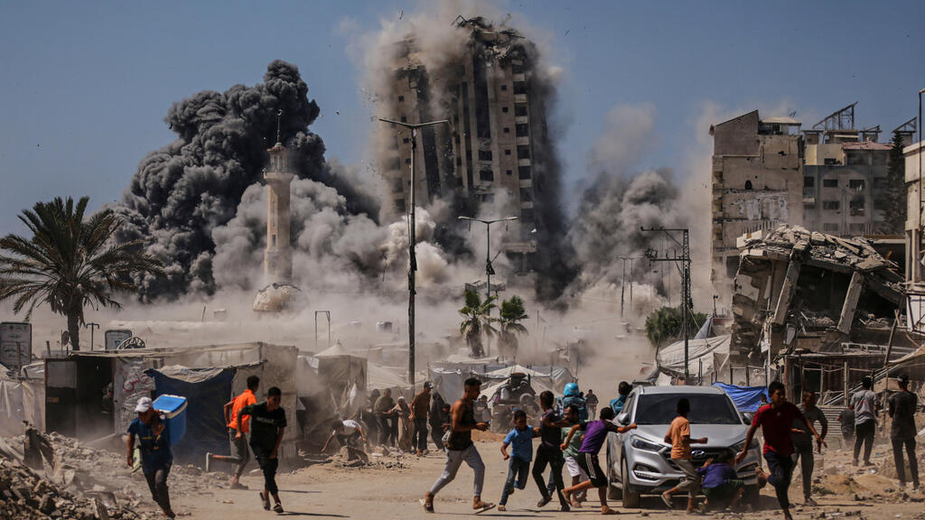 People run for cover during an Israeli airstrike on a high-rise building in Gaza City, Friday, Sept. 5, 2025, after the Israeli army issued a warning. (AP Photo/Yousef Al Zanoun)