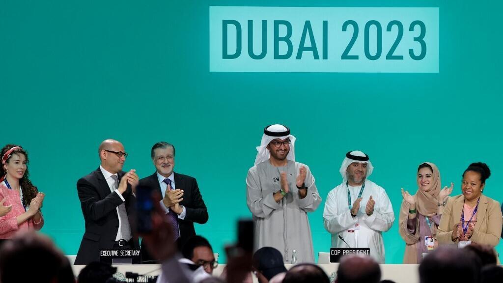 Le président de la COP28, Sultan Al-Jaber, et différents responsables de la conférence climat, se lèvent pour applaudir l'adoption du Bilan mondial de l'Accord de Paris, le 13 décembre 2023.