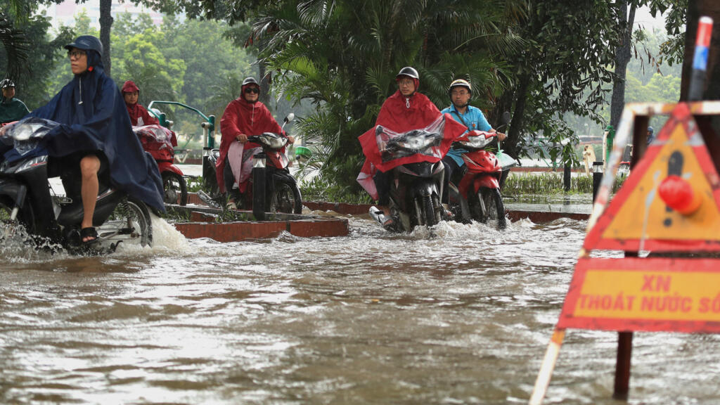 People drive motorcycles on a flooded street caused by Typhoon Kajiki in Hanoi, Vietnam, Tuesday, Aug. 26, 2025. (AP Photo/Huy Han)