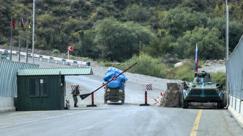 An Armenian resident of Nagorno-Karabakh drives past Russian peacekeepers after being checked by Azerbaijani border guards at the Lachin checkpoint on the road to Armenia in October 2023. Border routes like this are now reopening to cargo traffic for the first time in decades.