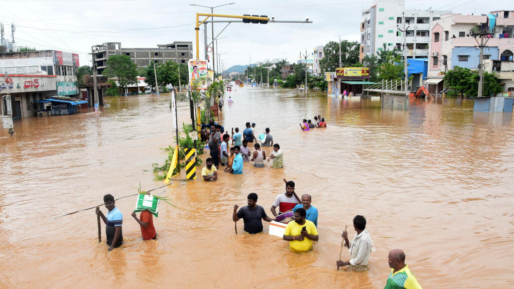 Les gens traversent des routes gorgées d'eau à la suite de fortes pluies à Vijayawada, dans l'État d'Andhra Pradesh, dans le sud de l'Inde, le 2 septembre 2024.