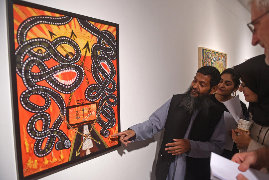 Ahmed Rabbani, un Pakistanais récemment libéré de la prison de Guantanamo Bay, montre sa peinture aux visiteurs lors d'une exposition de son travail intitulée : "The Unforgotten Moon : Liberating Art from Guantanamo Bay", à Karachi. Lorsque Rabbani a manqué de peinture pour satisfaire ses aspirations artistiques pendant 20 ans d'incarcération à Guantanamo Bay, il s'est tourné vers tout ce qui lui tombait sous la main - la saleté, le café moulu et même des épices comme le curcuma de la cantine de la prison.