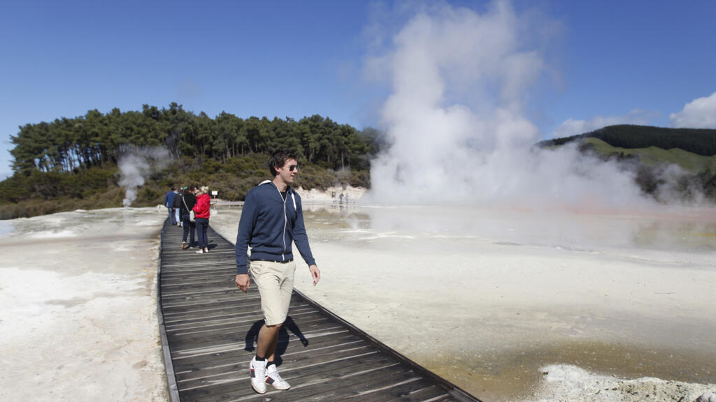 Des touristes marchent sur une passerelle en bois au-dessus d'un cratère dans la zone géothermique de Wai-O-Tapu à Rotorua, en Nouvelle-Zélande, le lundi 26 septembre 2011. Rotorua regorge de merveilles naturelles telles que des geysers, des piscines thermales et des boues bouillonnantes.