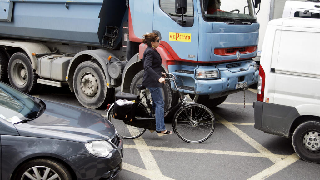 Uma ciclista tenta abrir caminho entre carros e caminhões no centro de Paris.
