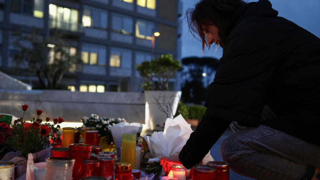 Uma mulher coloca uma vela na estátua do falecido Papa João Paulo II no Hospital Gemelli, onde o Papa Francisco está internado para tratamento contínuo de pneumonia, em Roma, Itália, em 12 de março de 2025.