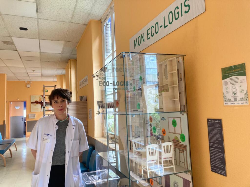Gaëlle Gilbert, logisticienne au sein de la maternité de l'hôpital de la Pitié-Salpêtrière-APHP, à côté de l'exposition "éco-logis", visible en salle d'attente et destinée à sensibiliser les futurs parents sur les bonnes pratiques en matière de santé et de développement durable.