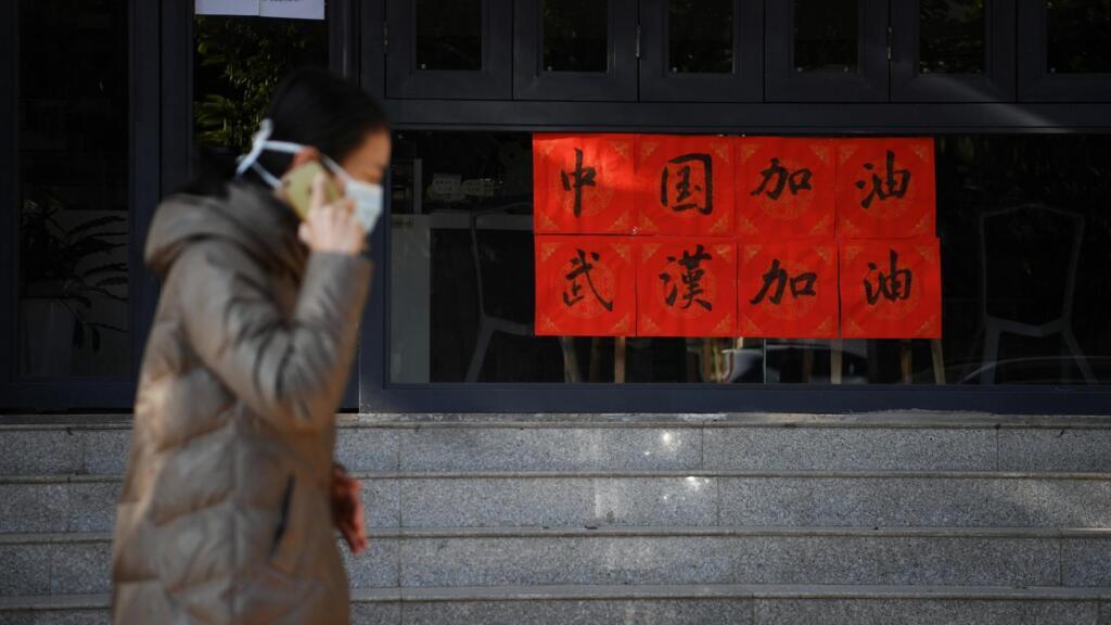 Une femme portant un masque passe devant un coffee shop à Kunming, dans la province du Yannan, le 2 février 2020, en Chine où le pays a décidé de fermer des milliers de ces boutiques pour éviter la propagation du 2019-nCoV.