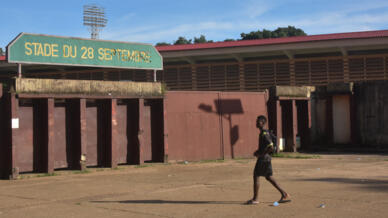 Un homme marche vers l'entrée du stade du 28-Septembre, à la veille de l'ouverture du procès des massacres de 2009.