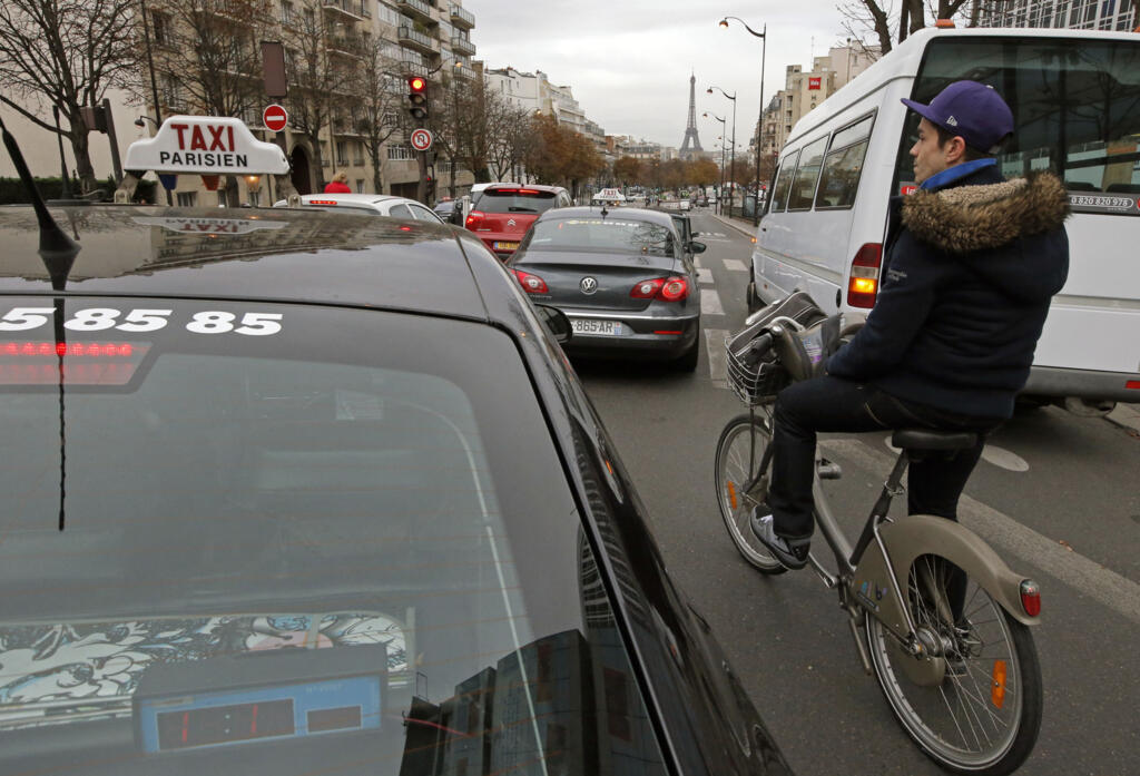 Ciclista precisa desviar de caminhonete estacionada para entrega em ciclovia de Paris.